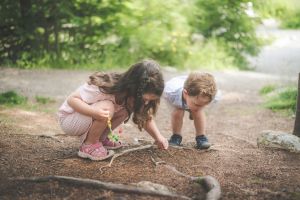 2 Kinder im Wald, die den Boden untersuchen