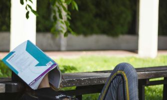 Ein Kind liegt im Schatten mit einem Buch auf dem Kopf