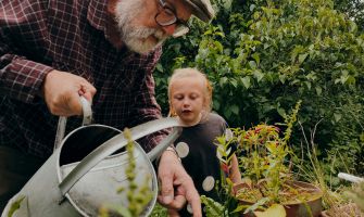 Ein Mann zeigt einem Kind das Blumengießen