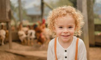 Ein glückliches Kind, im Hintergrund Hühner