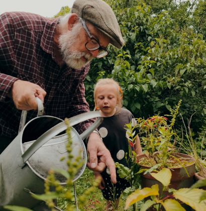 Ein Mann zeigt einem Kind das Blumengießen