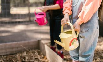Kinder, die eine bunte Gießkanne in der Hand haben