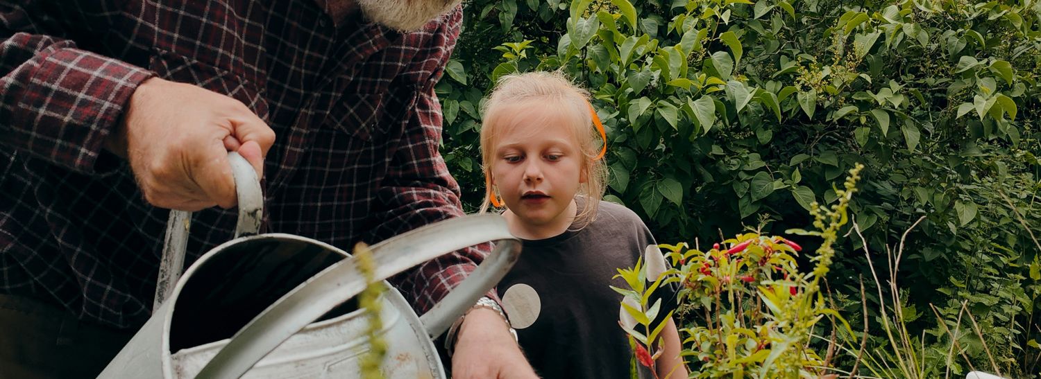 Ein Mann zeigt einem Kind das Blumengießen