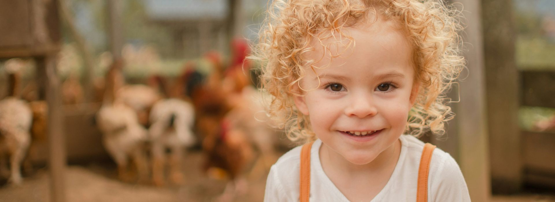 Ein glückliches Kind, im Hintergrund Hühner