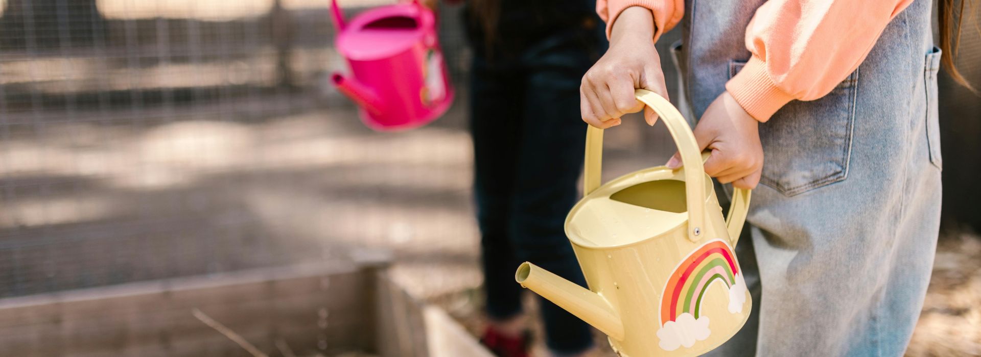 Kinder, die eine bunte Gießkanne in der Hand haben