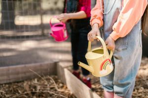 Kinder, die eine bunte Gießkanne in der Hand haben