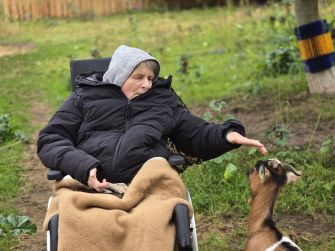 Eine ältere Frau, die eine Ziege streichelt